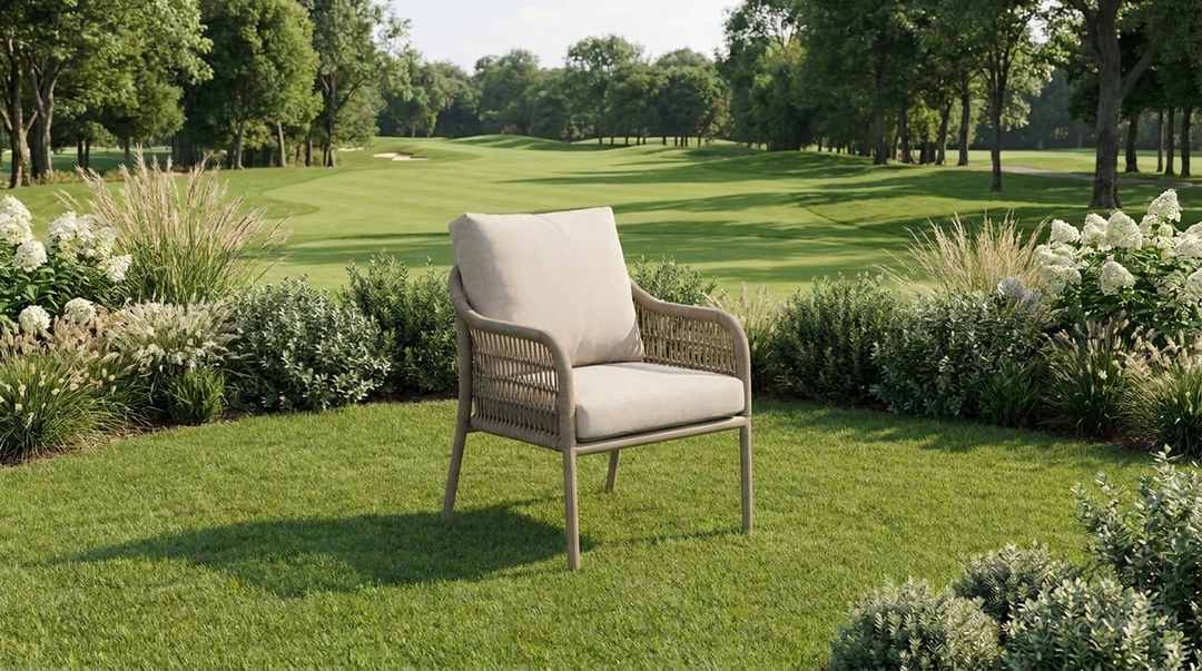 Rounded woven outdoor lounge chair with beige cushions in a garden